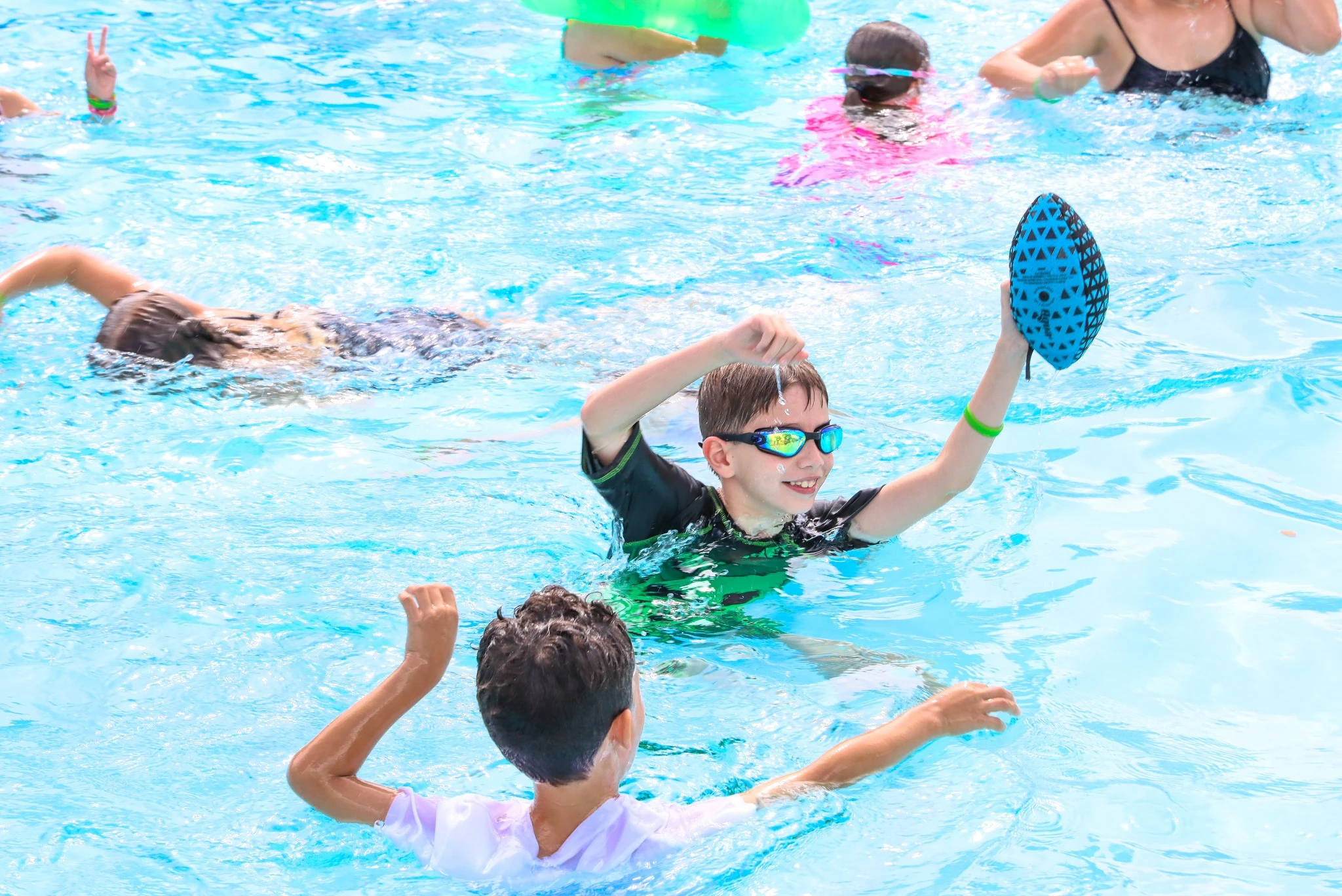 Children playing water games in a pool at summer camp in Boynton Beach