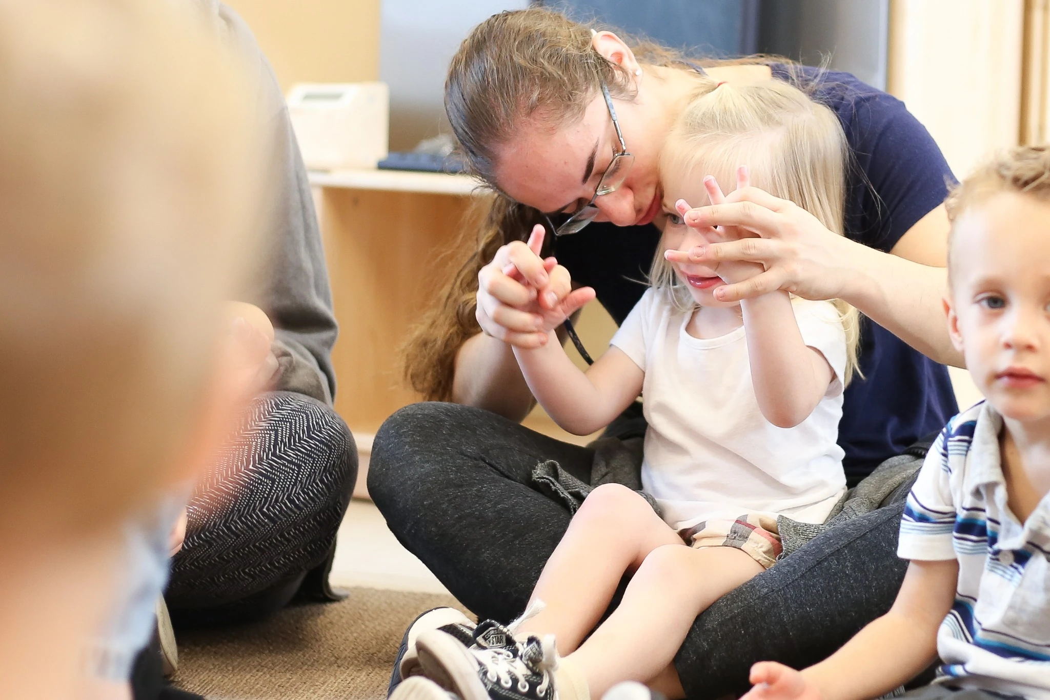 JCC aftercare teacher helping a young child during a classroom group activity