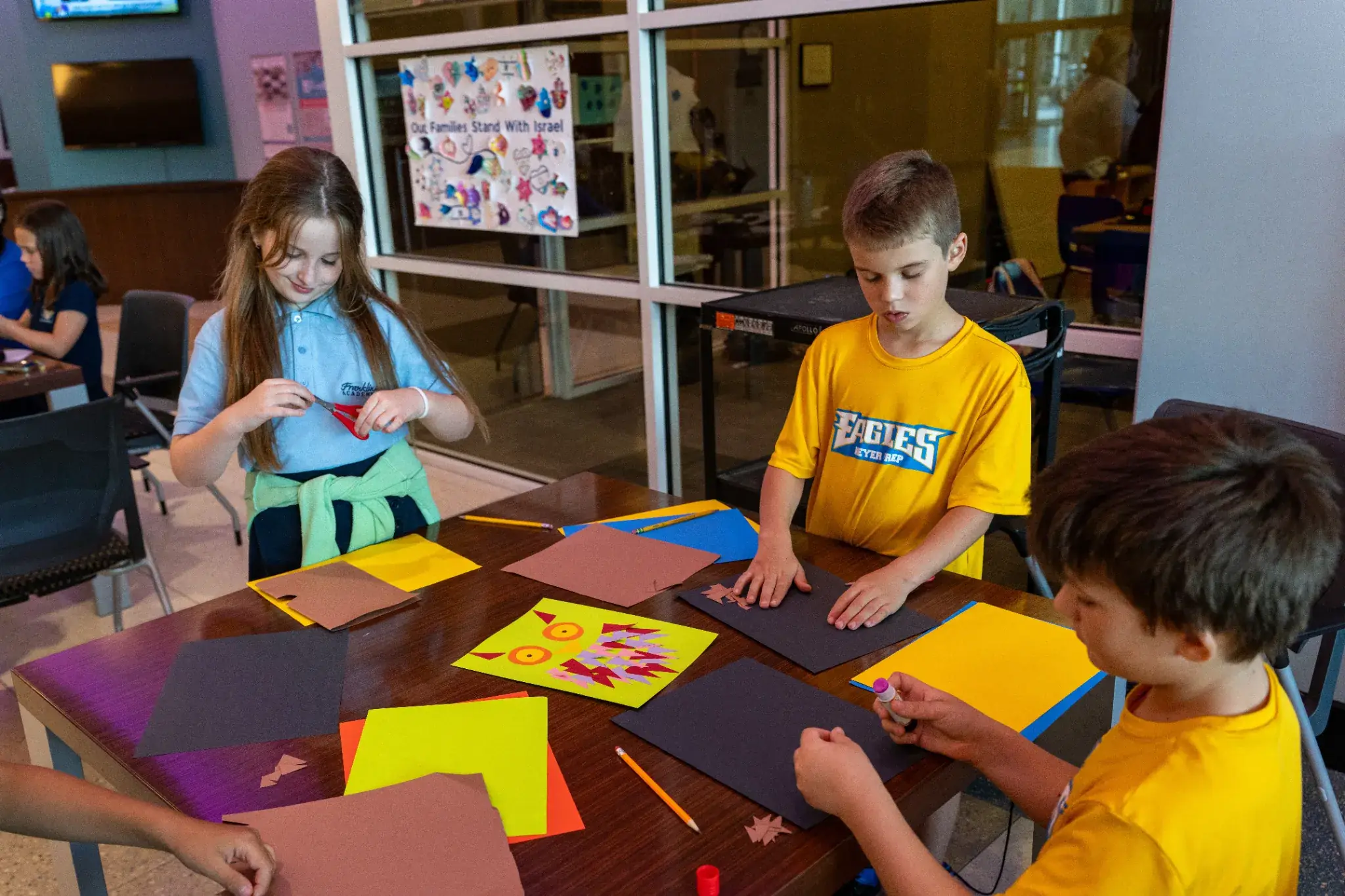 Children participating in arts and crafts activities during JCC Aftercare, creating colorful paper projects together in a classroom setting