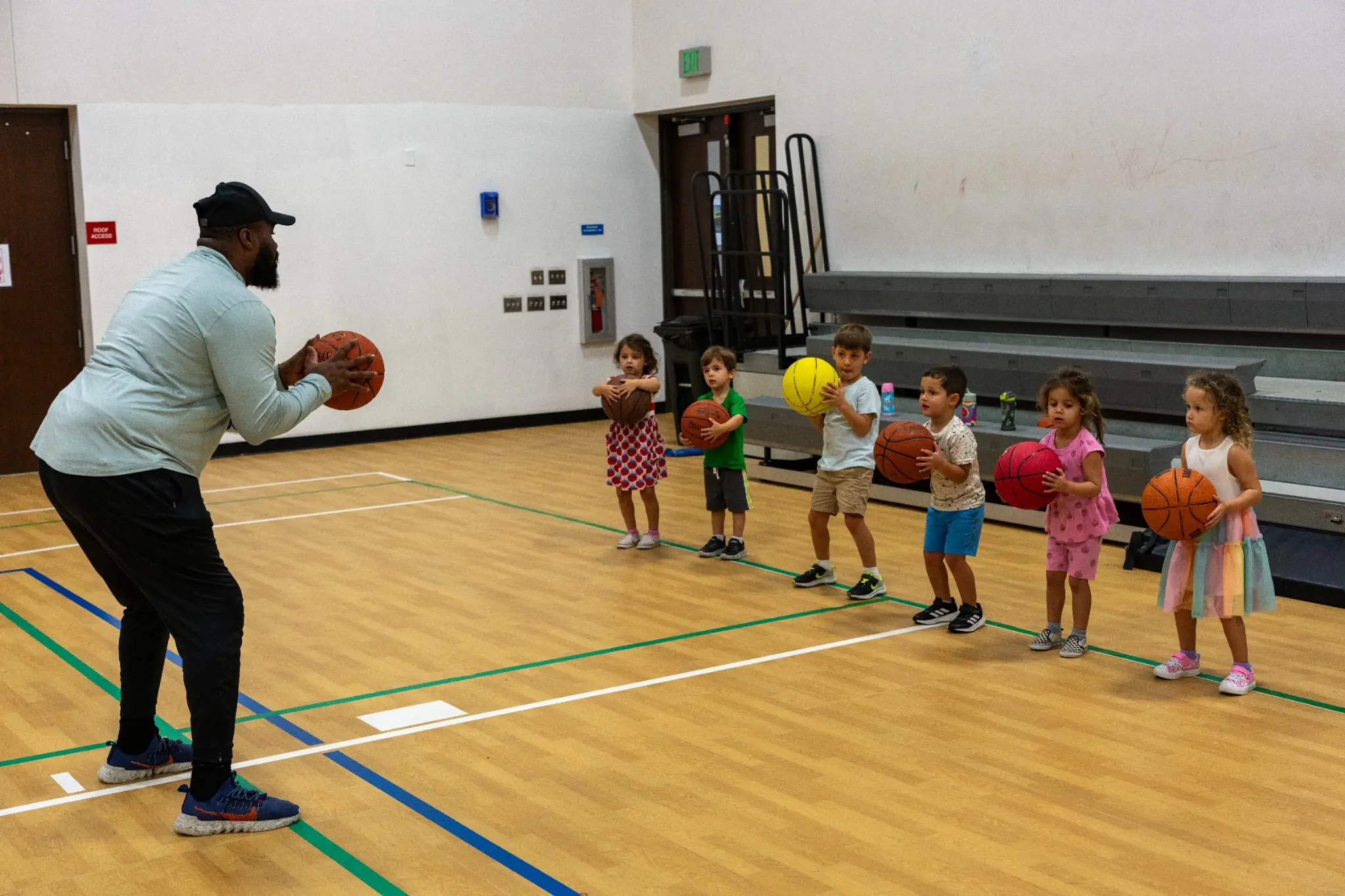 Young children learning basketball fundamentals with an instructor during JCC hours and early childhood sports programs