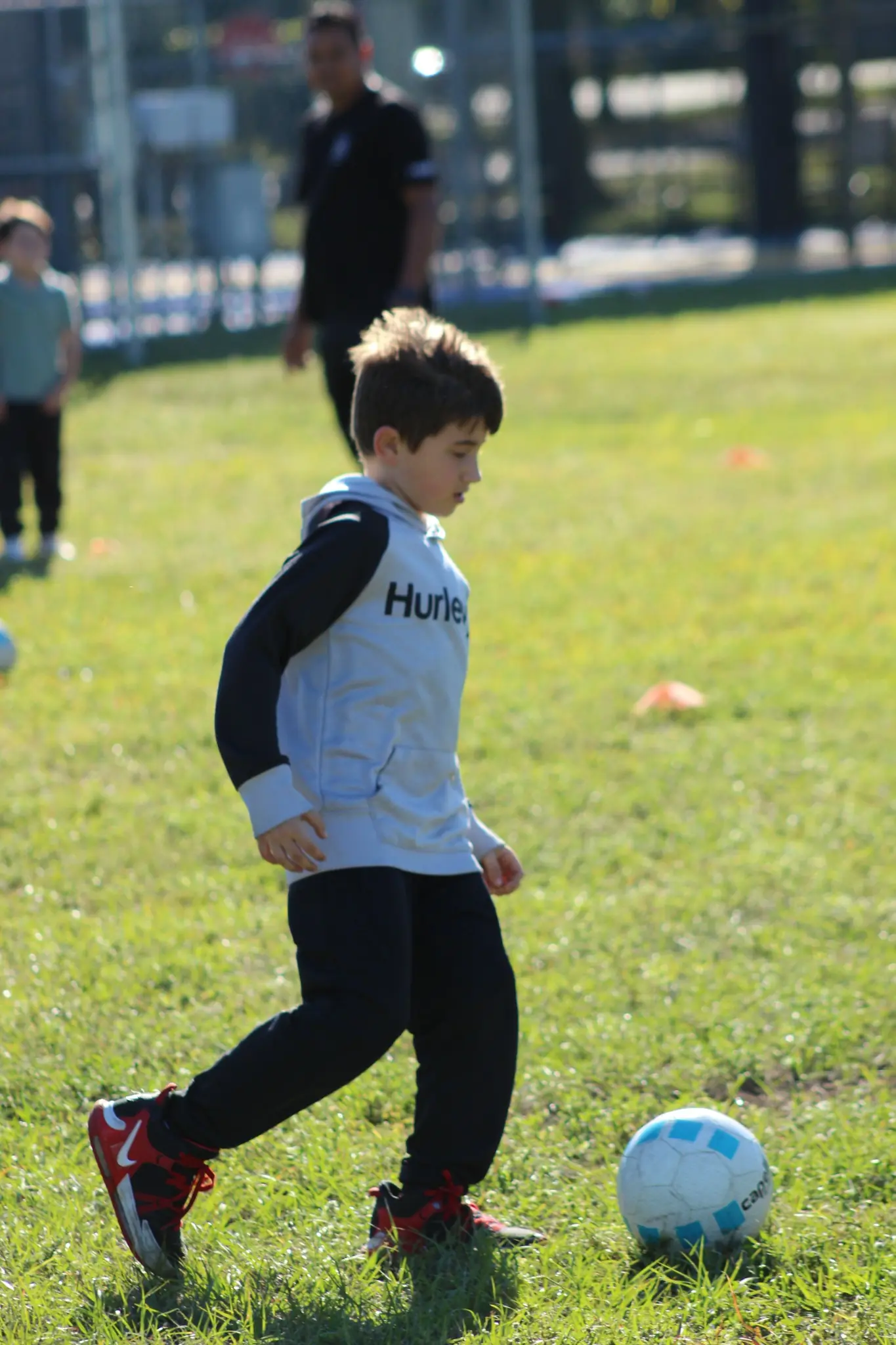 Young child participating in a soccer skills session on a grassy field during JCC classes and sports programs