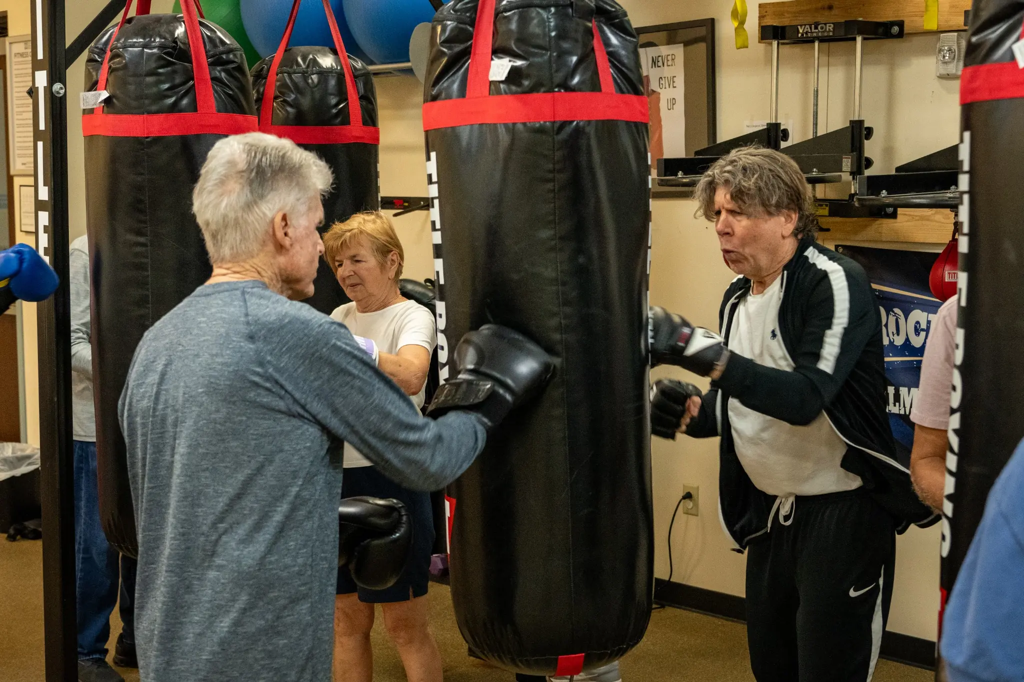 Older adults participating in a boxing fitness workout with heavy bags during JCC classes and wellness programs
