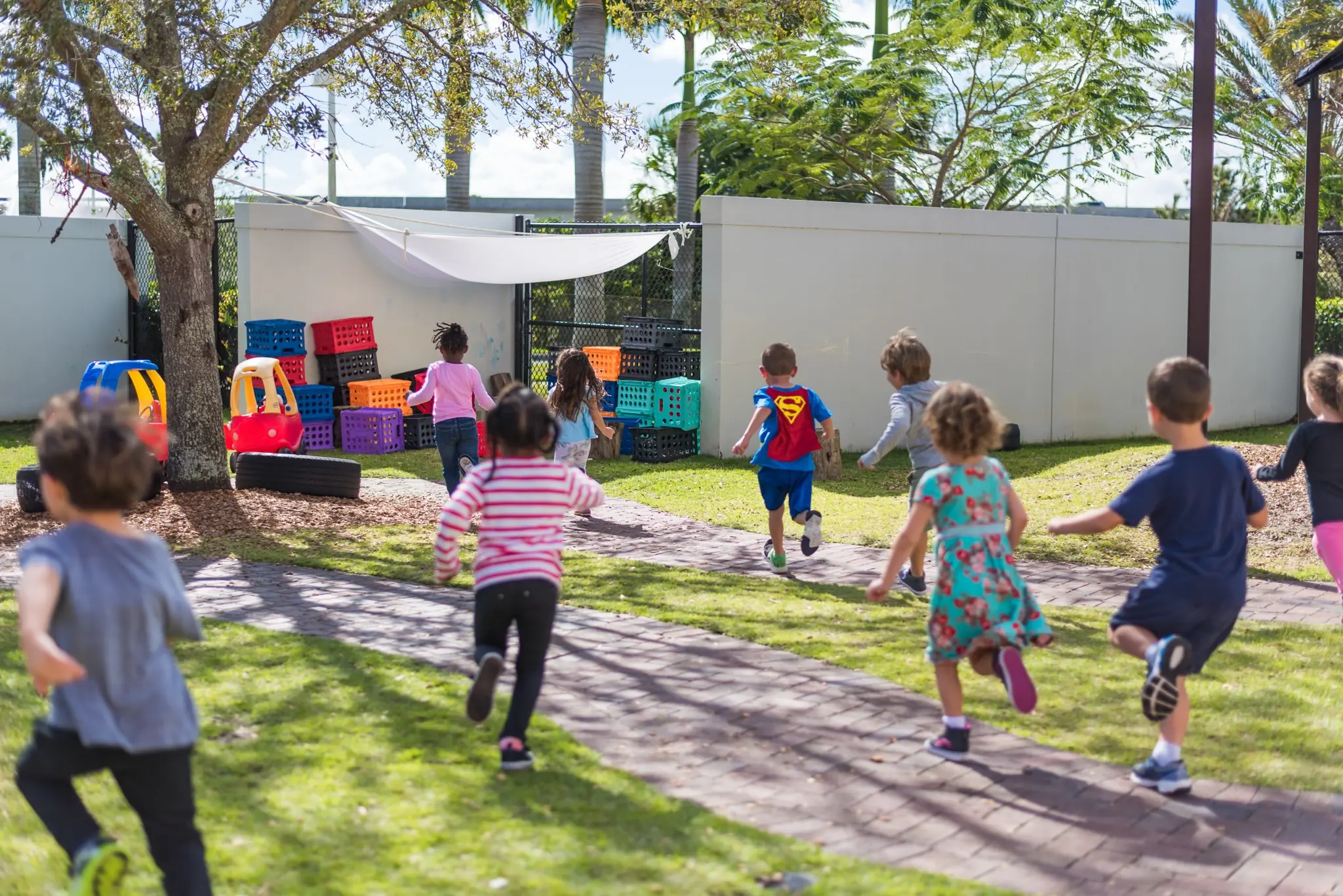 Preschool children running and playing together outdoors during a JCC preschool program