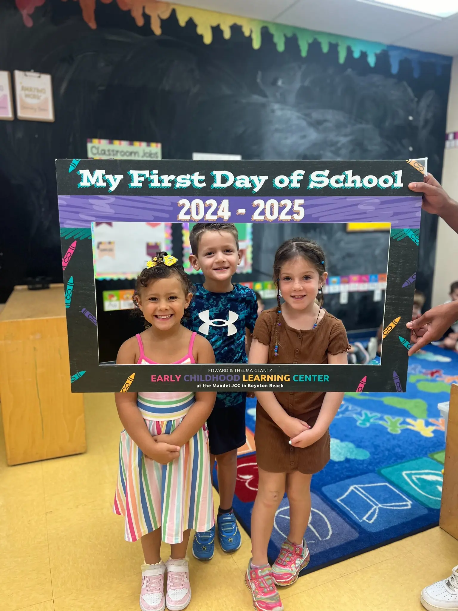 Preschool children posing for a first day of school photo at a JCC early childhood learning center