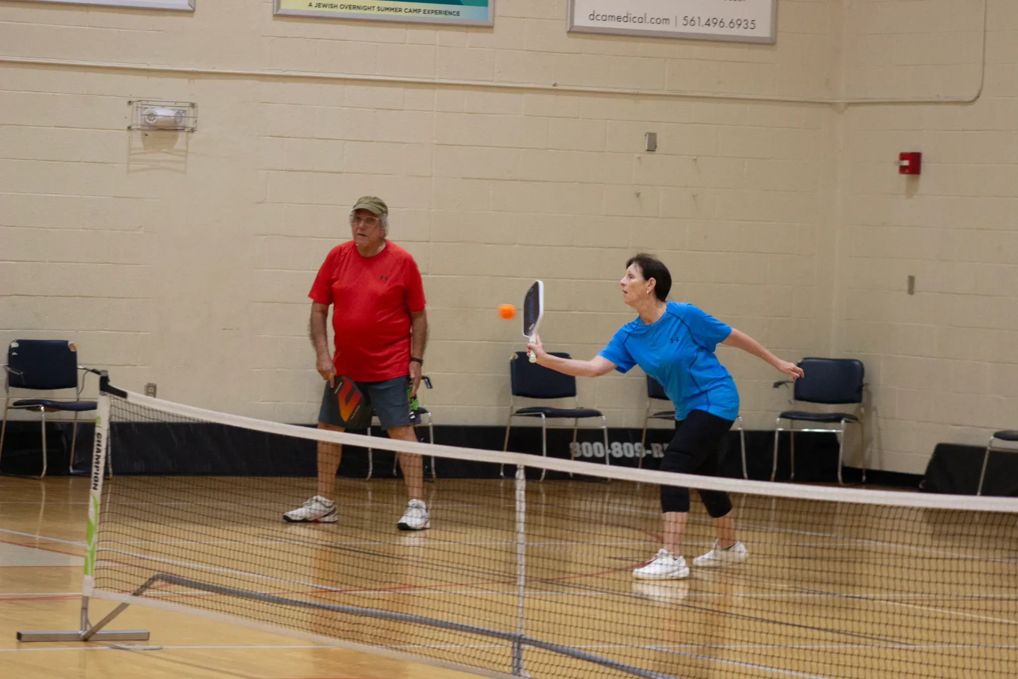 Two adults taking doubles pickleball lessons in boynton beach during a recreational fitness program at the Mandel JCC.