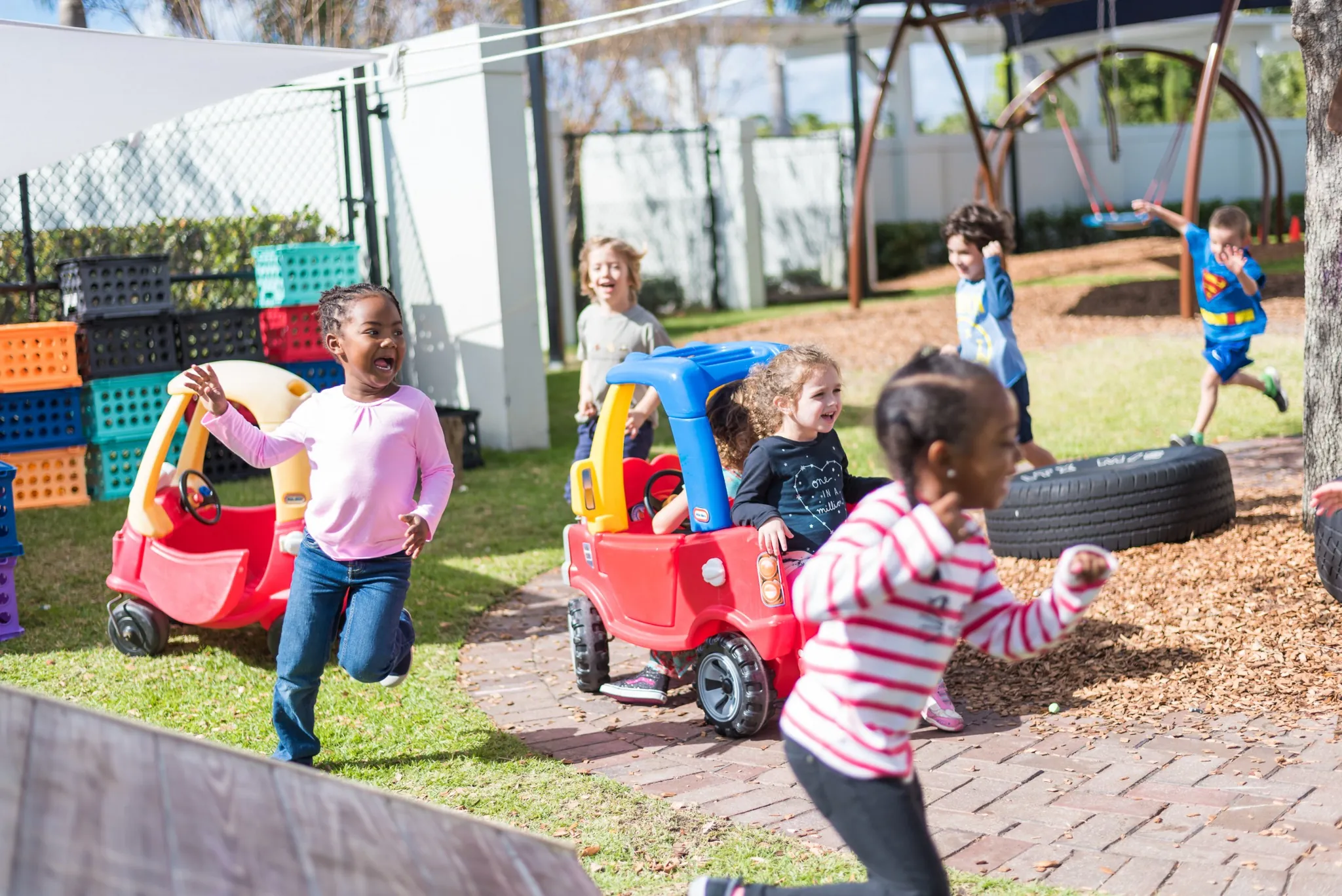 Children enjoying active outdoor play during early childhood JCC classes in a supervised playground