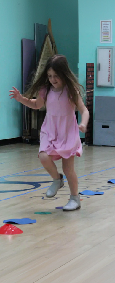 preschooler takes her turn playing hopscotch learning game with her class at preschool boynton beach fl