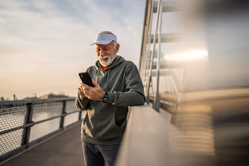 Older man checking his phone on a bridge while using Nina, NCH's 24/7 heart care guide.
