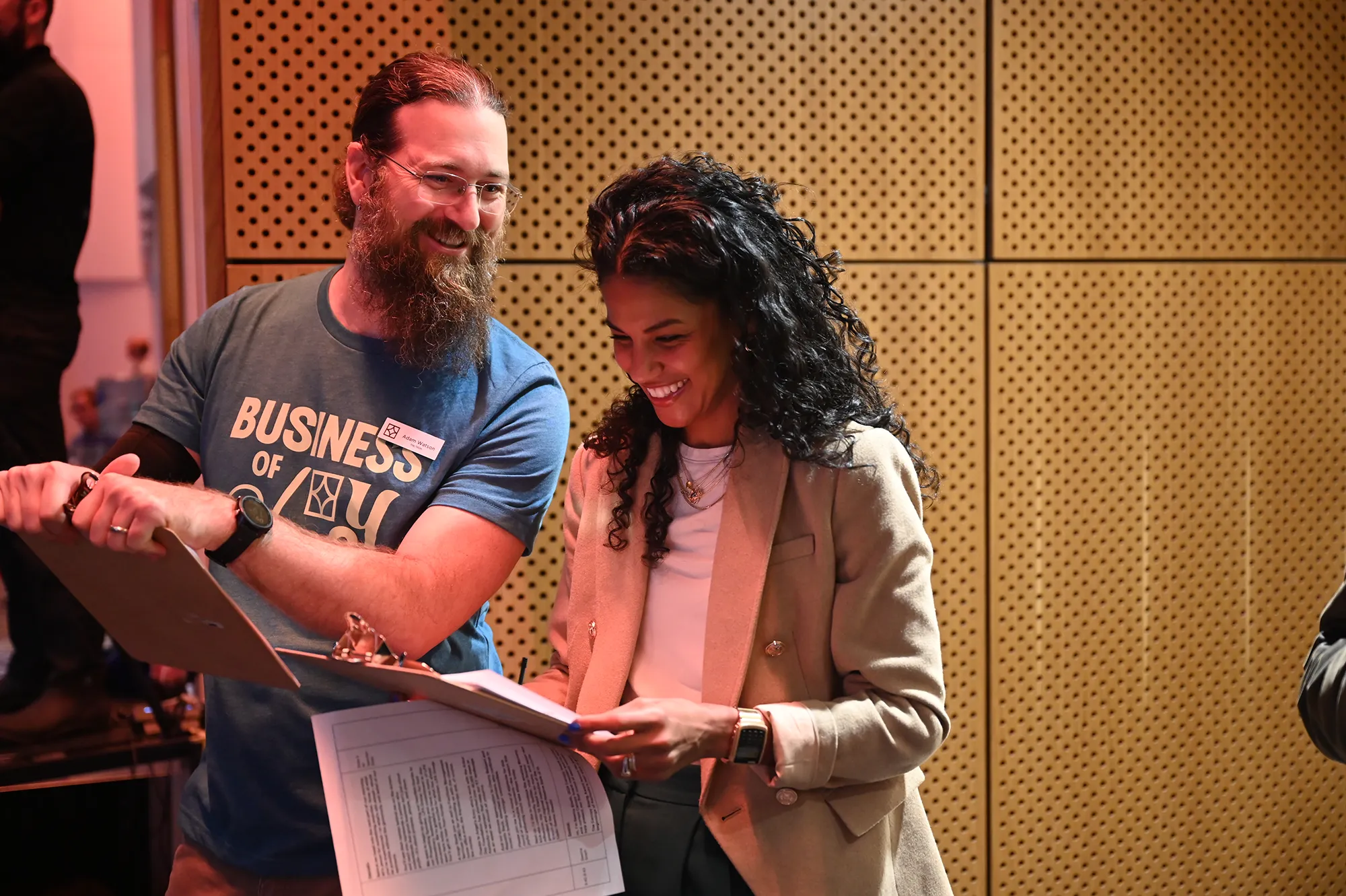 Smiling man and woman reviewing documents together in a professional setting.