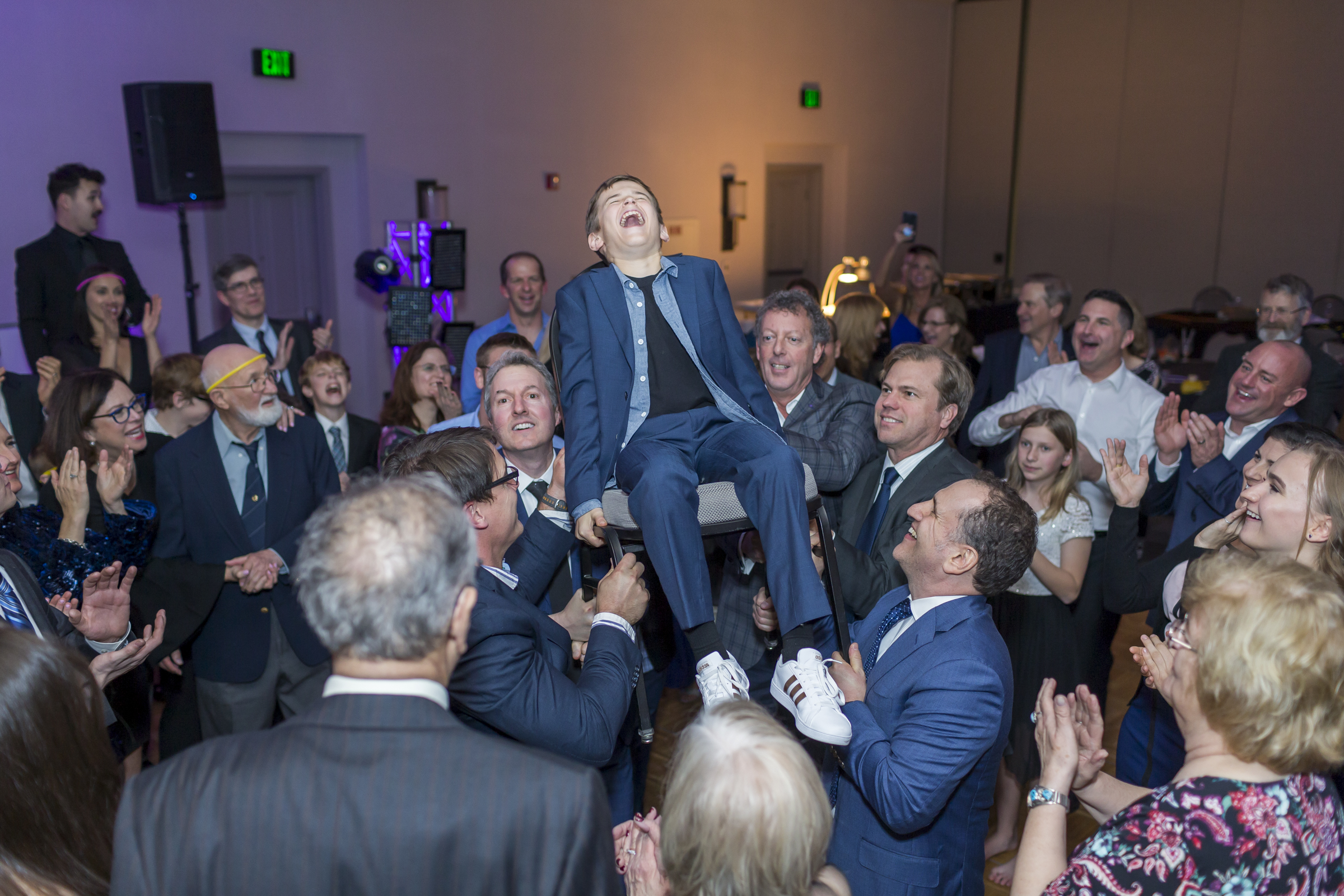 Young man celebrating Mitzvah in a chair being held by family