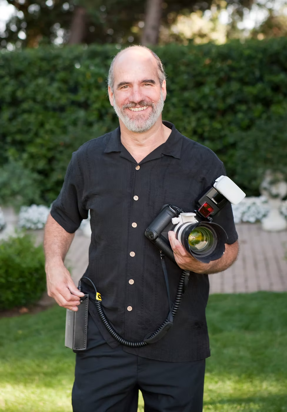 Bob Stender smiling for the camera while holding a camera with a mounted flash