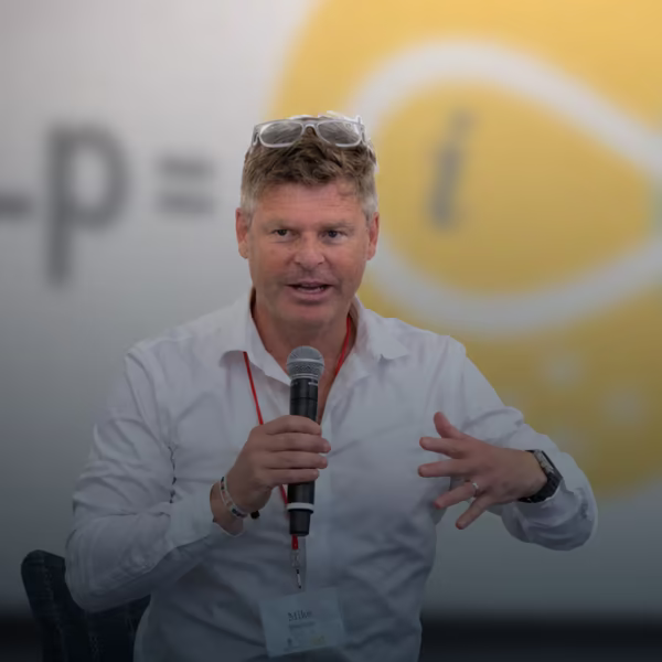 Mike Hutchins speaking with a microphone in front of the Leadership Equation graphic