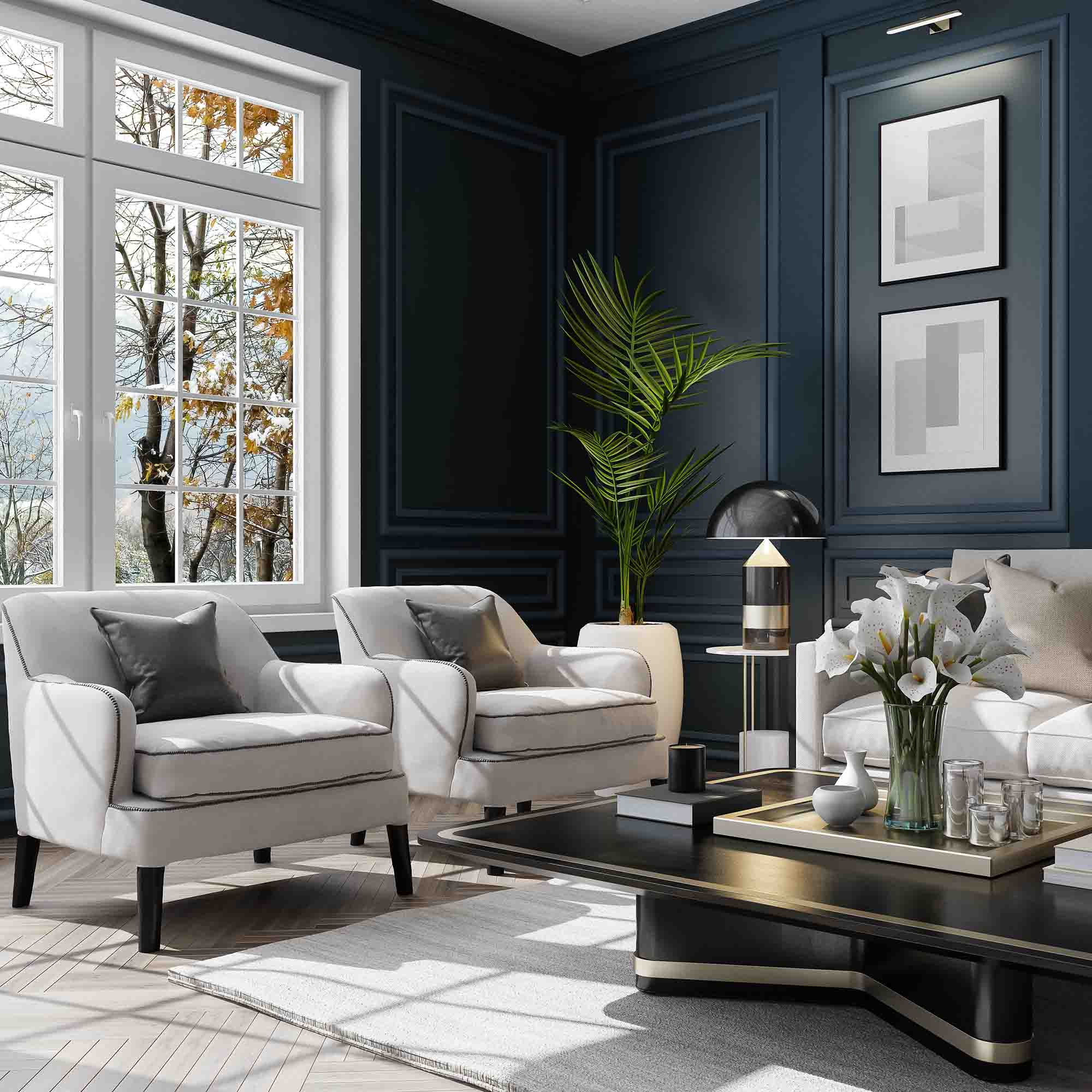 Bright living room with two white armchairs, a white sofa, dark paneled walls, large window showing autumn trees, and a black coffee table with flowers and decorative items.
