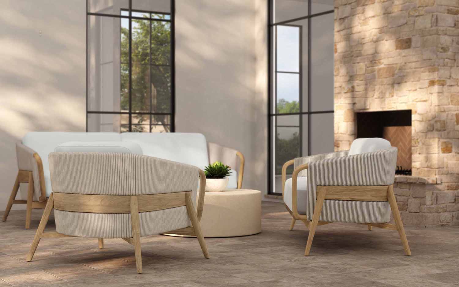 Modern living room with beige armchairs, white sofa, round ottoman, and stone fireplace.
