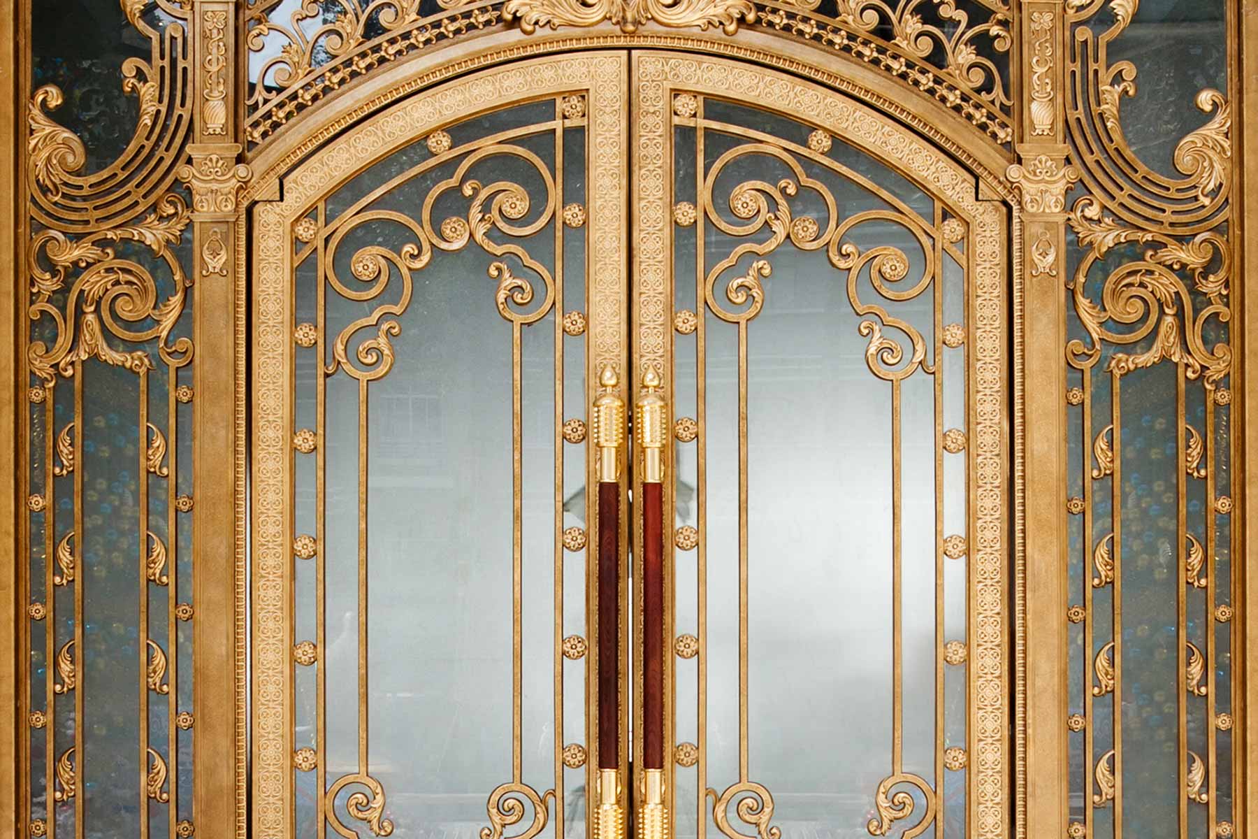 Ornate golden double doors with intricate scrollwork and glass panels.