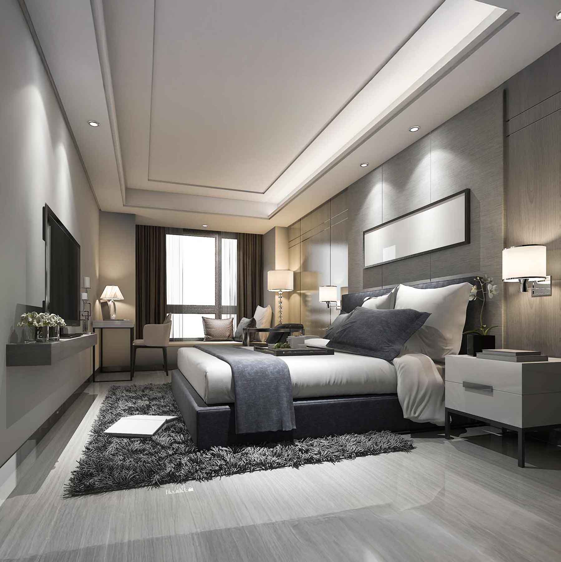 Modern hotel bedroom with a large bed, gray bedding, bedside tables, lamps, and a TV mounted on the wall.