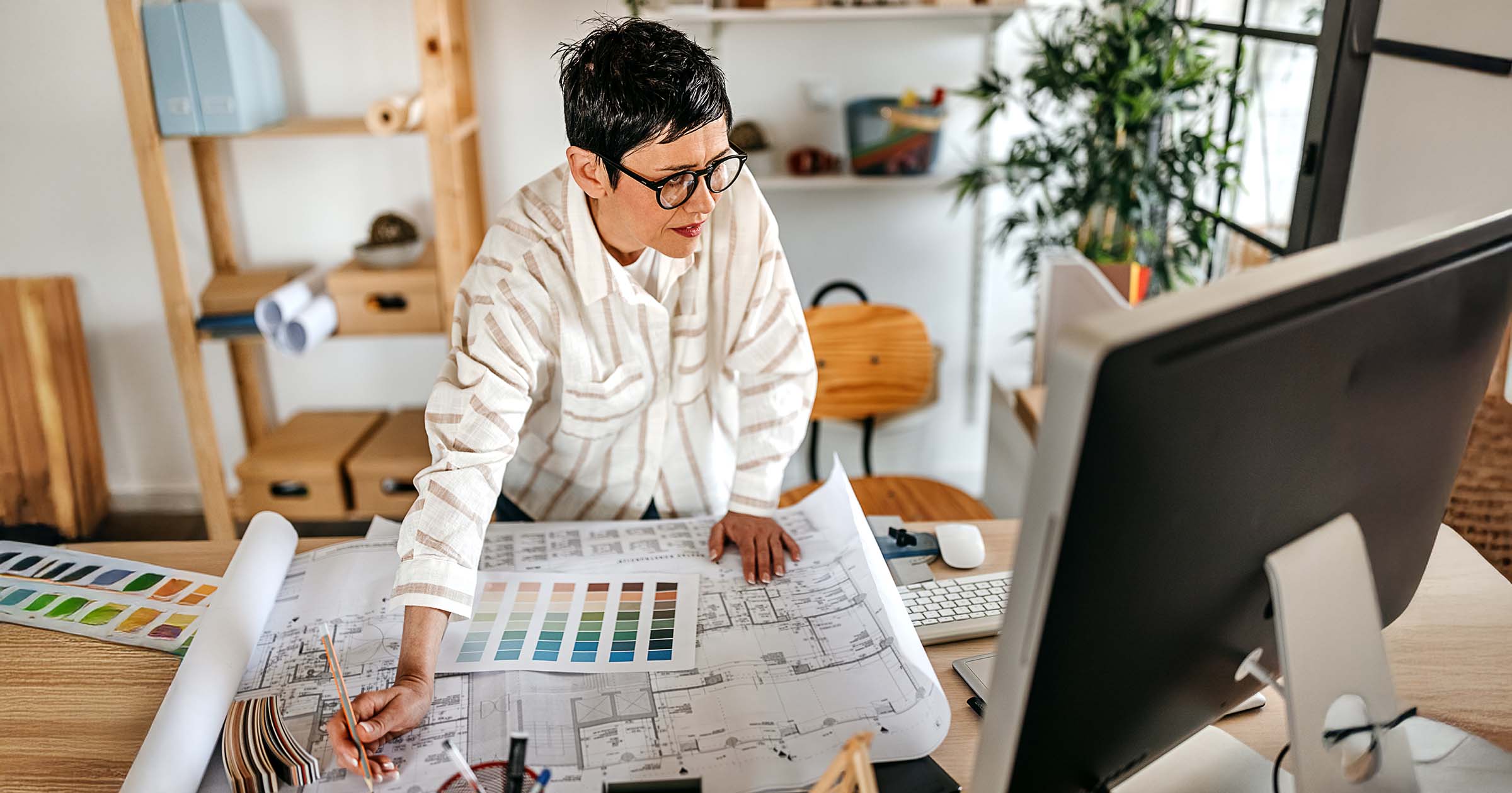 Interior designer reviewing architectural blueprints and color swatches at a desk with a computer contacting Sterling Collective