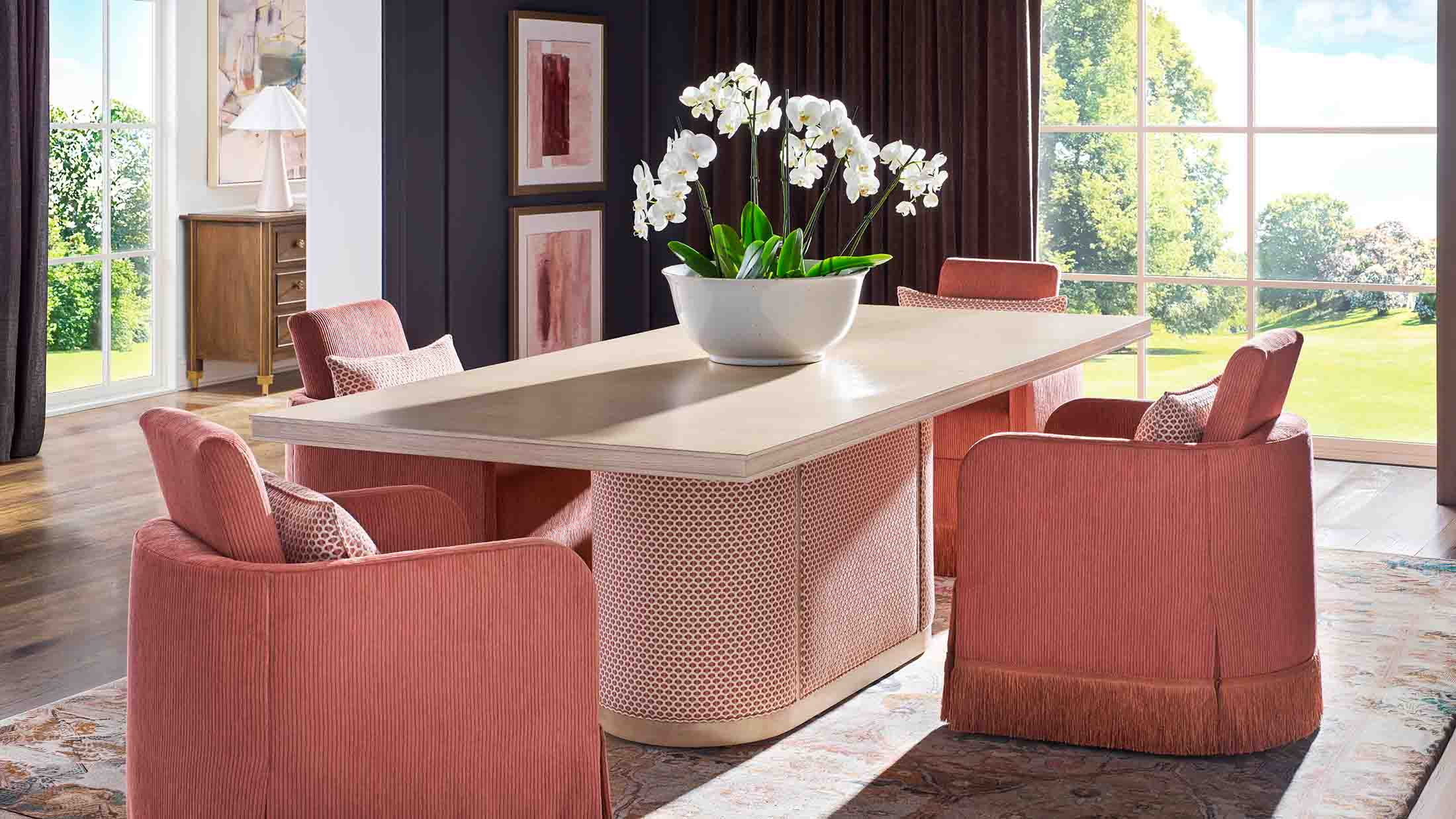 Vanguard Furniture presents a modern dining room with light wood table, coral upholstered chairs, and white orchid centerpiece.