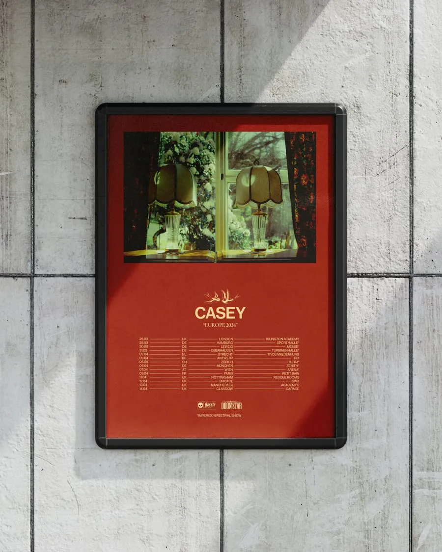 Framed poster on a tiled wall showing Casey Europe 2024 tour dates with a photo of two lamps in front of a window at the top.