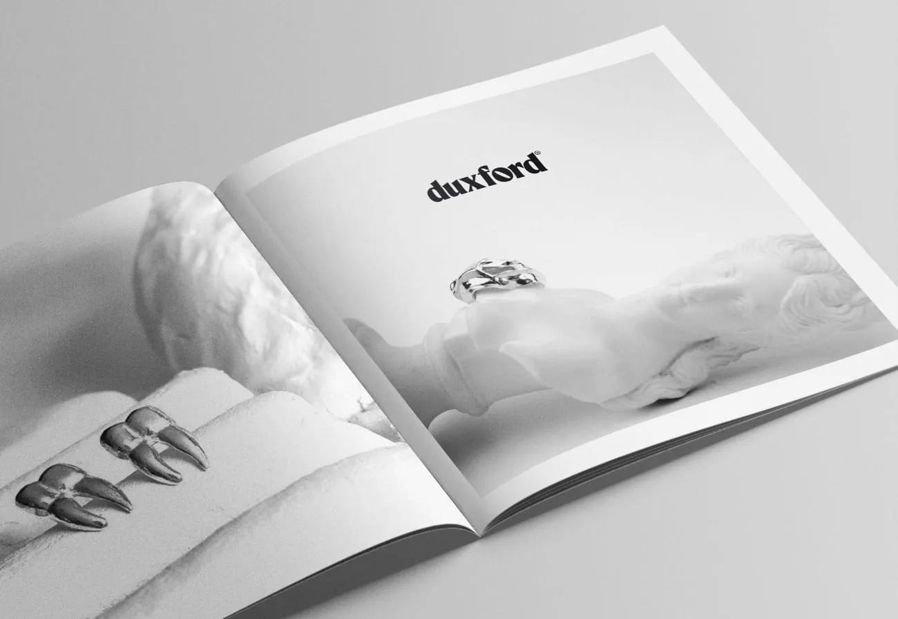 Open magazine featuring silver rings displayed on a white sculpture bust with the brand name 'duxford' on a light background.