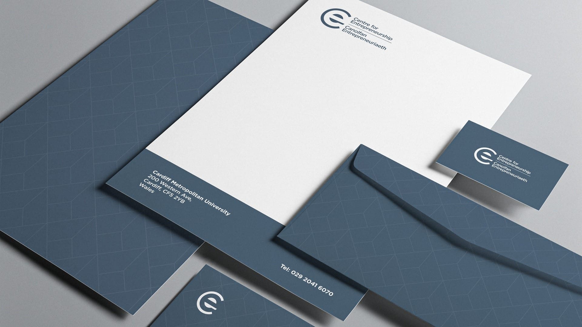 Stationery set including letterhead, envelope, and business card for Cardiff Metropolitan University's Centre for Entrepreneurship, featuring a blue geometric design.