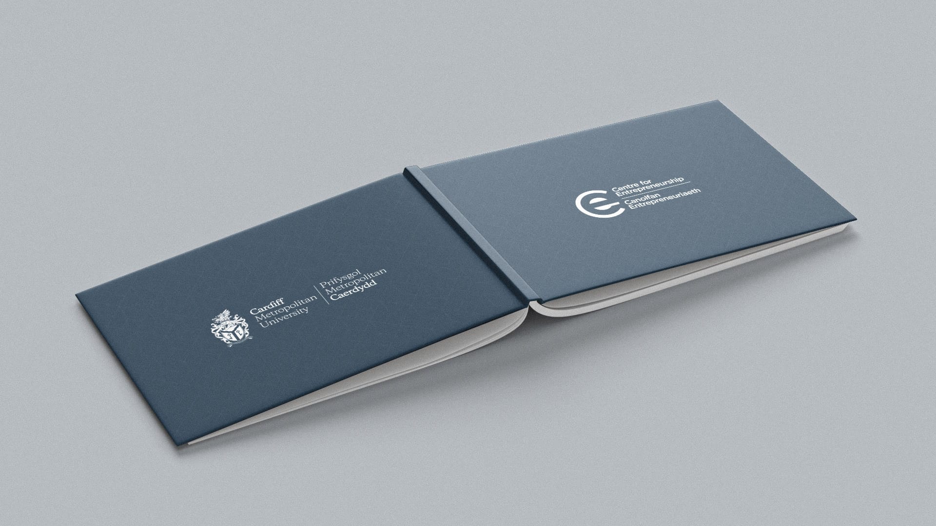 An open blue booklet displaying Cardiff Metropolitan University logo and Centre for Entrepreneurship logo on a grey surface.