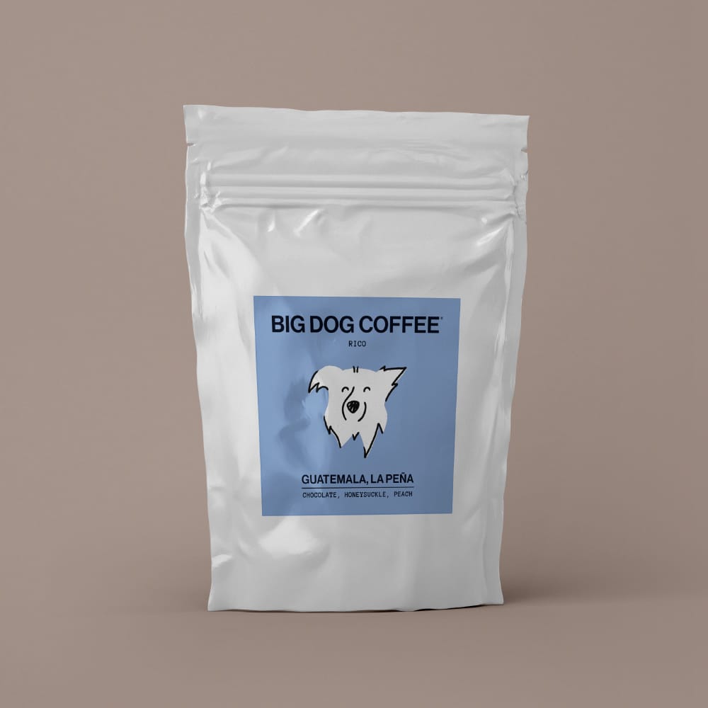 White resealable coffee bag with a blue label featuring a smiling dog illustration, labeled Big Dog Coffee from Guatemala, La Peña with chocolate, honeysuckle, and peach notes.