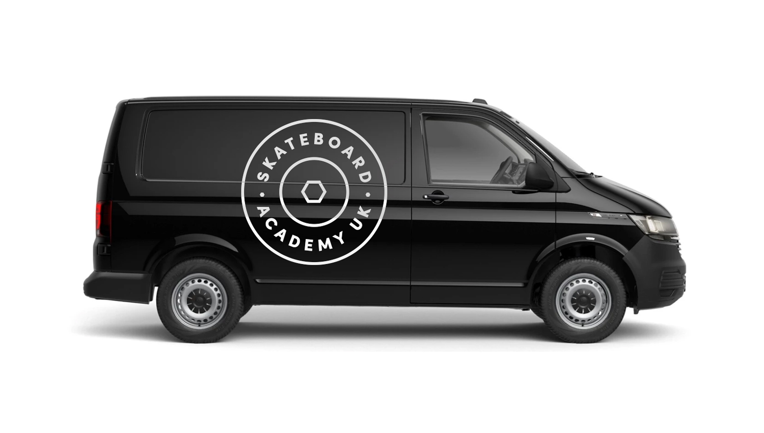 Black van with Skateboard Academy UK logo featuring a hexagonal bolt design on the side.