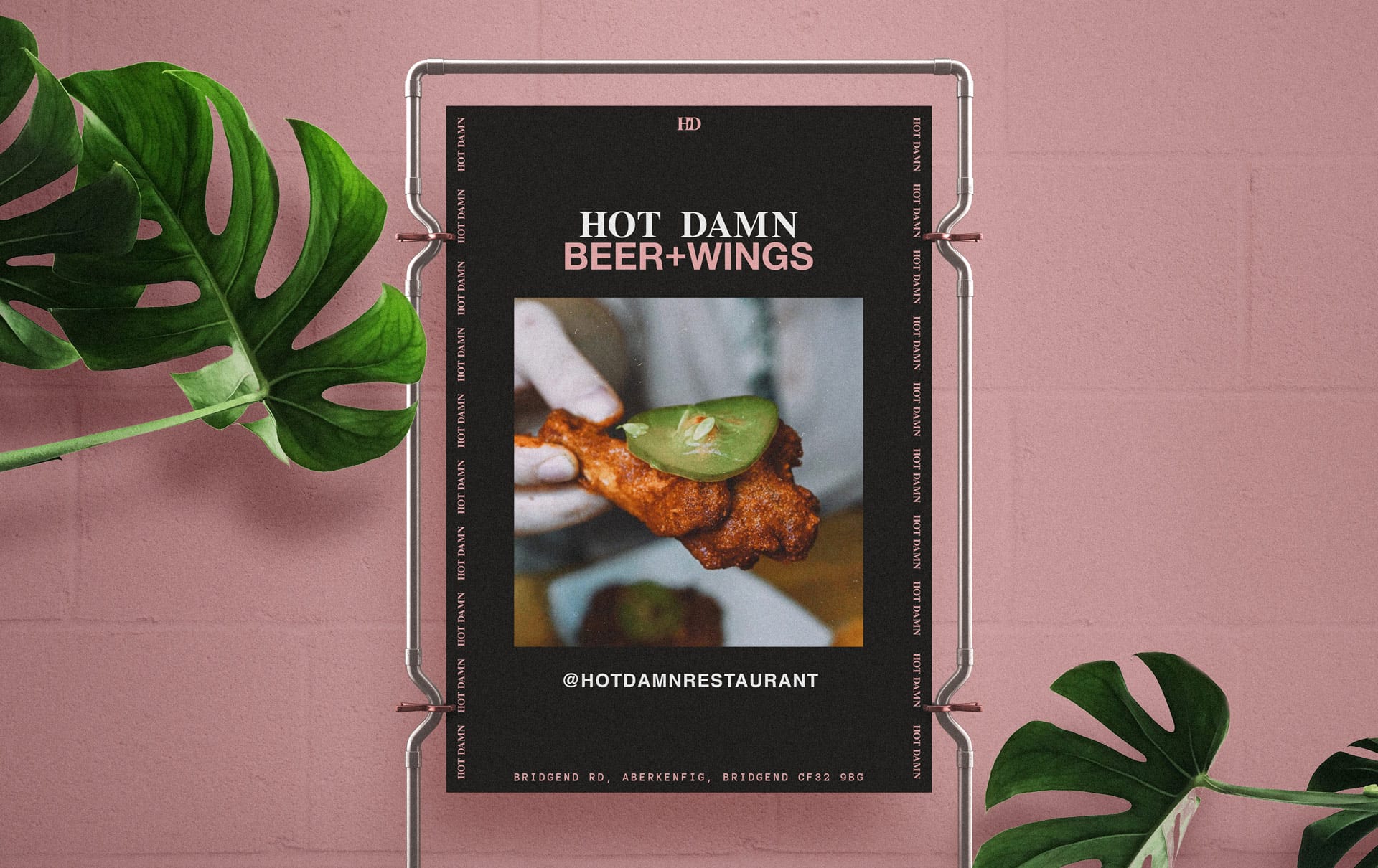 Advertisement poster for Hot Damn Beer and Wings featuring a hand holding a seasoned chicken wing topped with a slice of jalapeño.