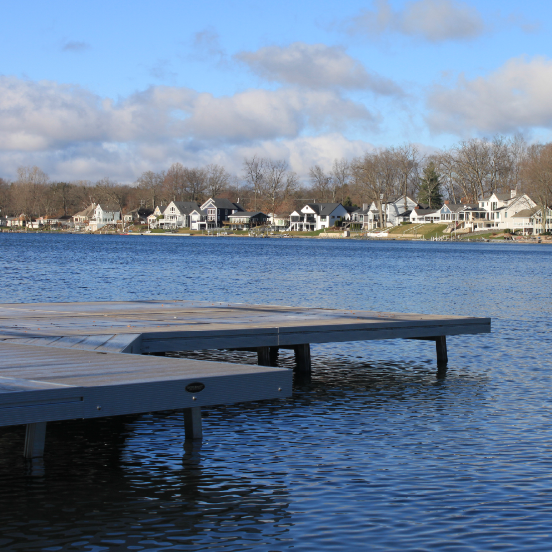 Lakefront dock with a boat lift and homes along the shoreline