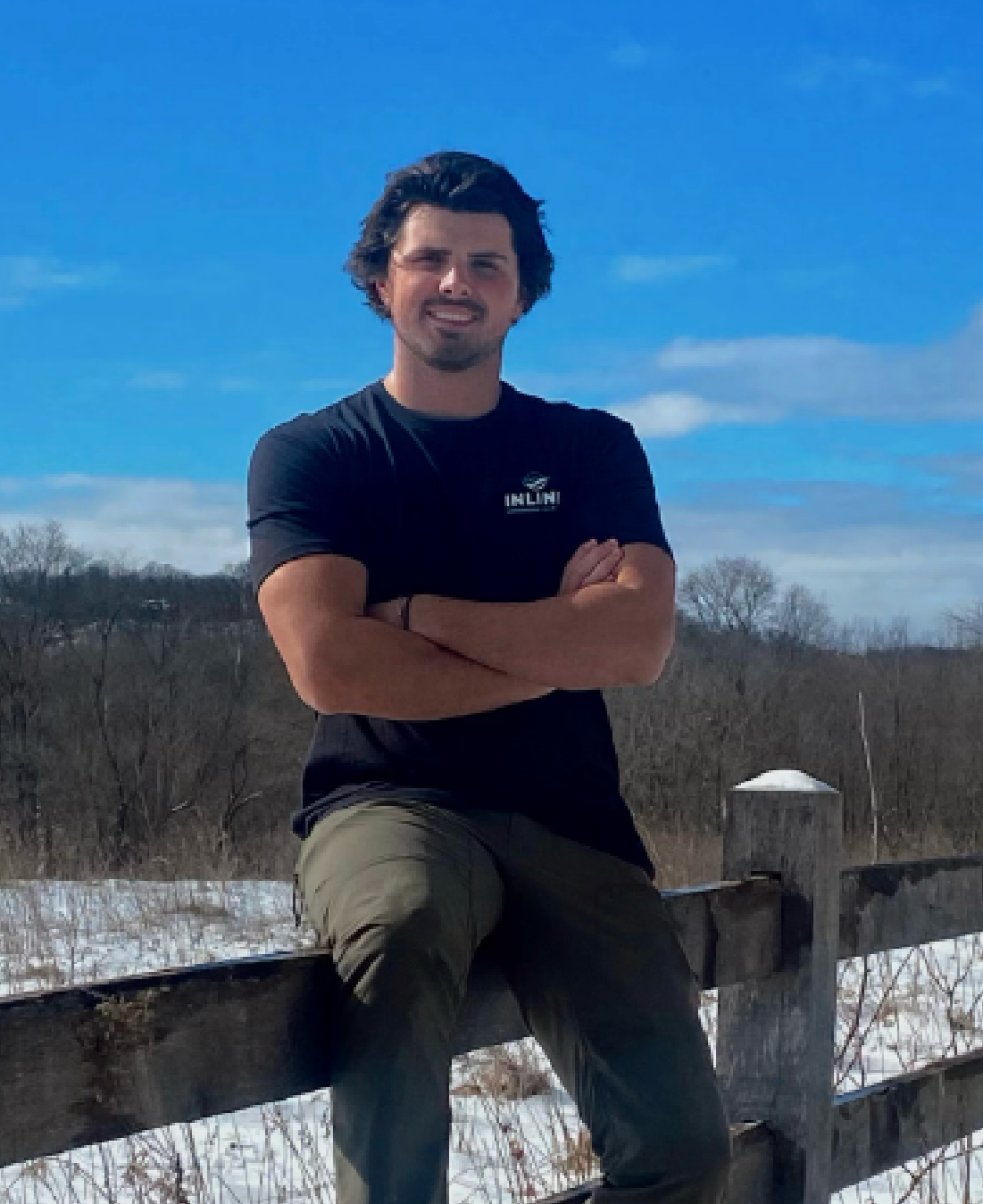 Gabe Rhoda, founder of Inline Marine, sitting on a wooden fence outdoors