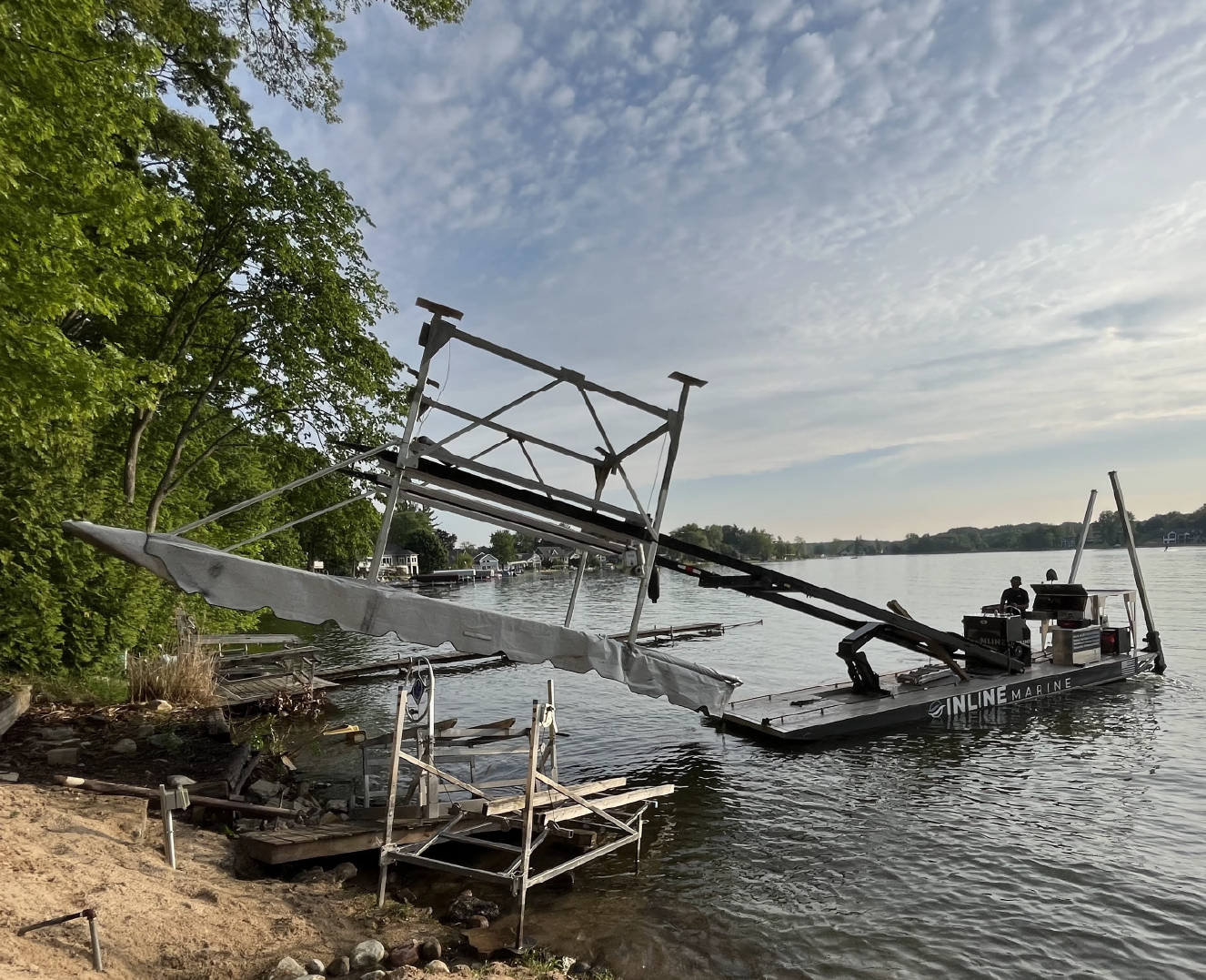 Fork barge lifting equipment along a wooded lake shoreline