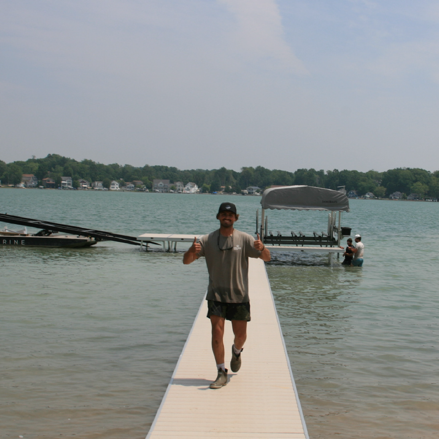 Inline Marine team member walking down a lakefront dock with a pontoon boat lift behind him