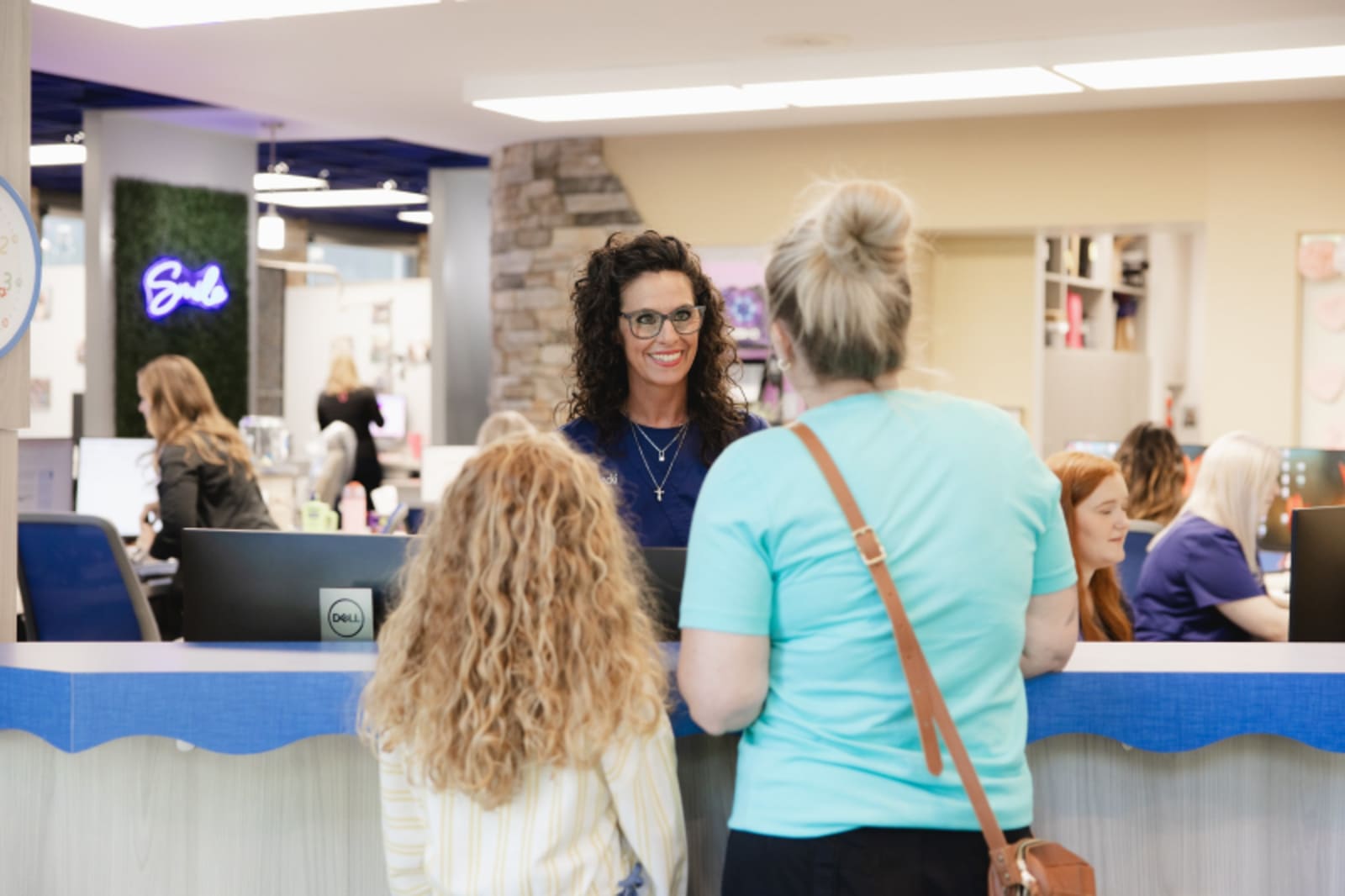 Receptionist assisting young patients at the front desk check-in area