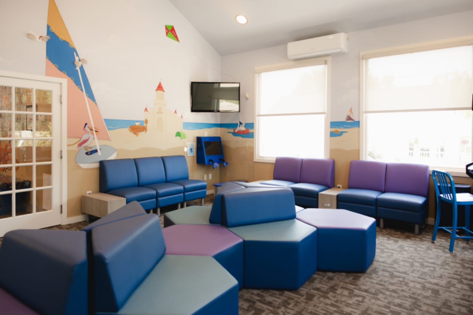 Modern waiting room with colorful ocean-themed wall mural and comfortable blue seating