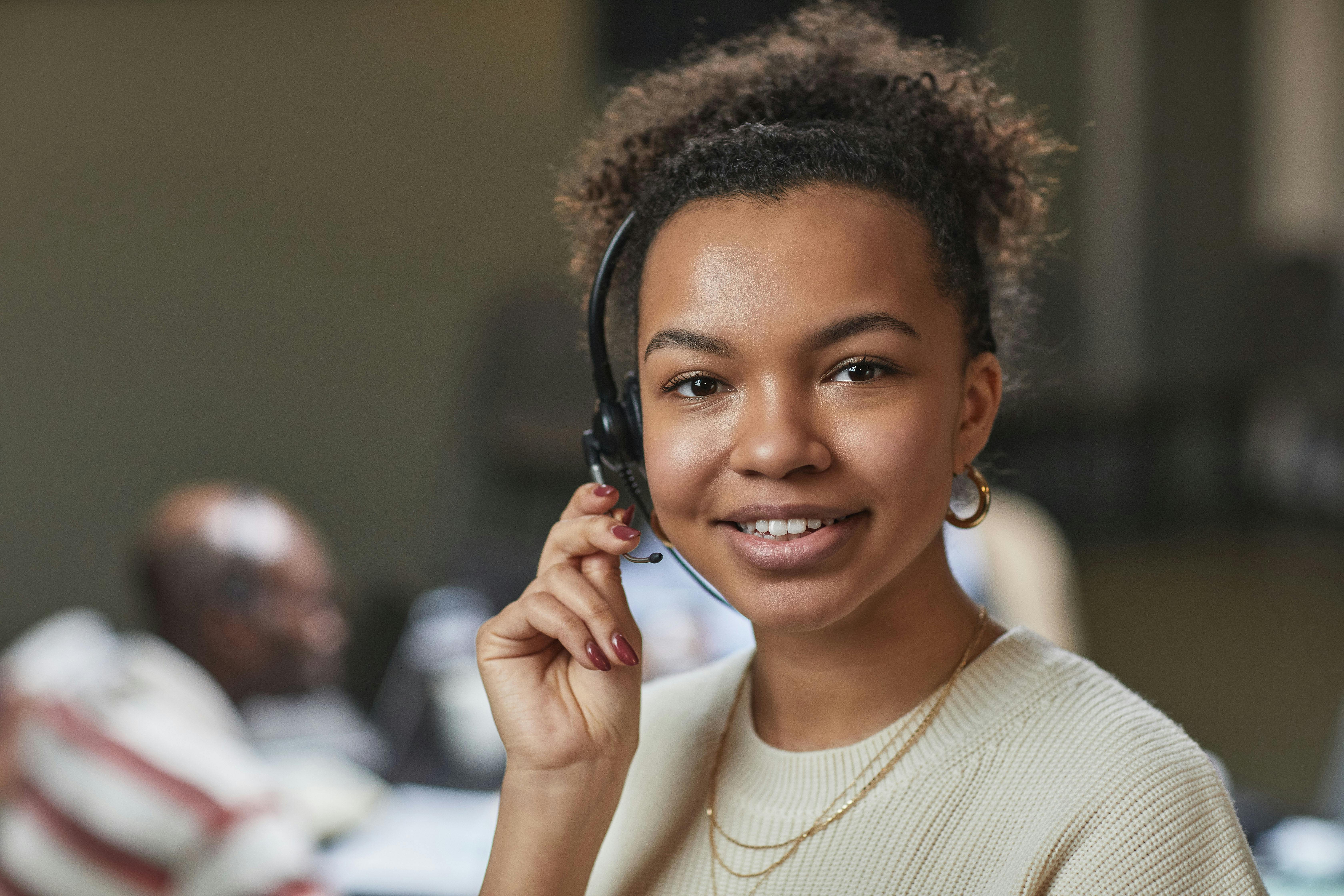 Jeune femme souriante portant un casque avec micro dans un centre d'appel.