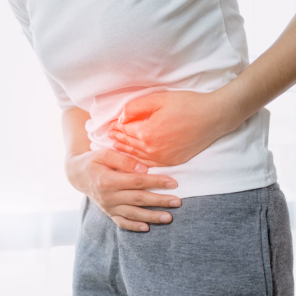 Person holding their lower abdomen due to abdominal pain, illustrating symptoms commonly associated with Inflammatory Bowel Disease (IBD).