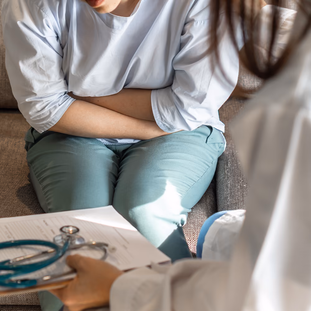 Patient experiencing abdominal discomfort while consulting with a healthcare professional about symptoms of irritable bowel syndrome (IBS).