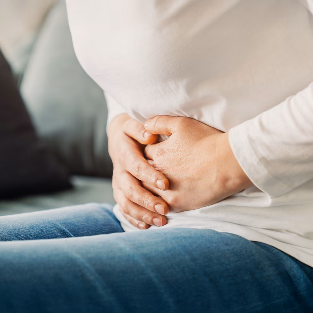 Person holding their abdomen due to stomach pain, illustrating abdominal discomfort commonly associated with irritable bowel syndrome (IBS).