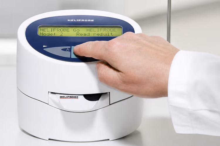 Healthcare professional preparing a Helicobacter pylori breath test device to assess a patient for H. pylori infection.