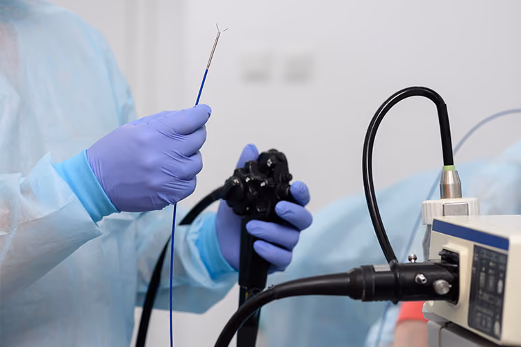 Healthcare professional holding an endoscope and biopsy forceps while preparing for an open access endoscopy procedure in a clinical setting.