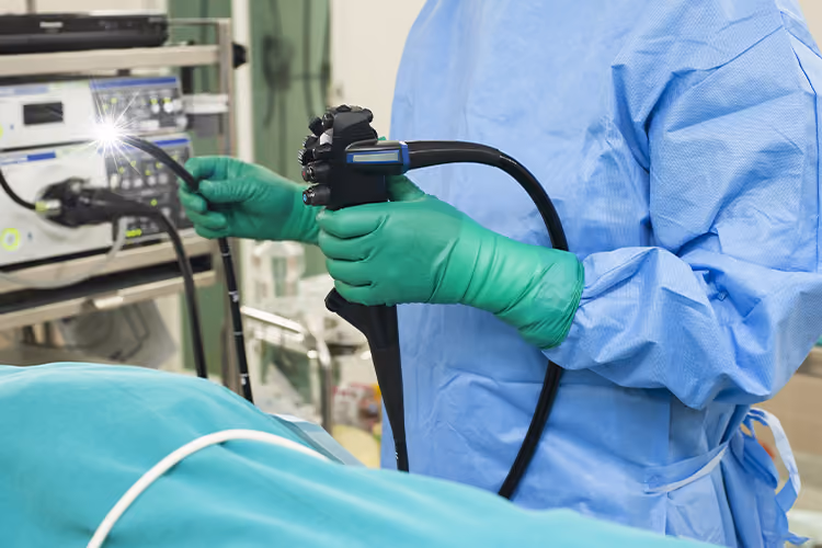 Healthcare professional preparing a colonoscope before performing a colonoscopy procedure in a modern endoscopy suite.