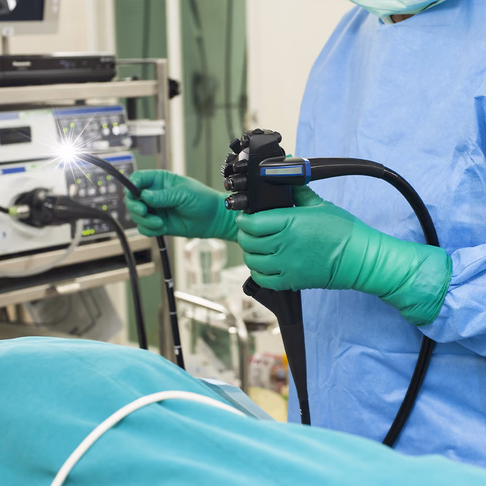 Healthcare professional preparing a colonoscope before performing a colonoscopy procedure in a modern endoscopy suite.
