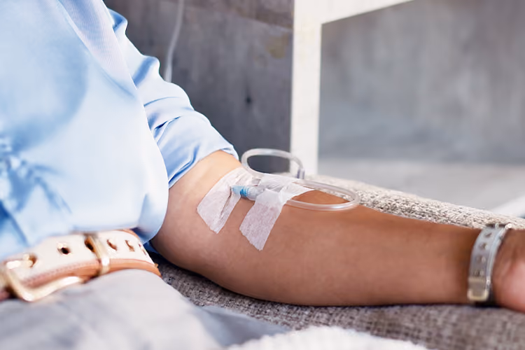 Close-up of a patient receiving a vitamin infusion through an IV cannula in a comfortable clinical setting.