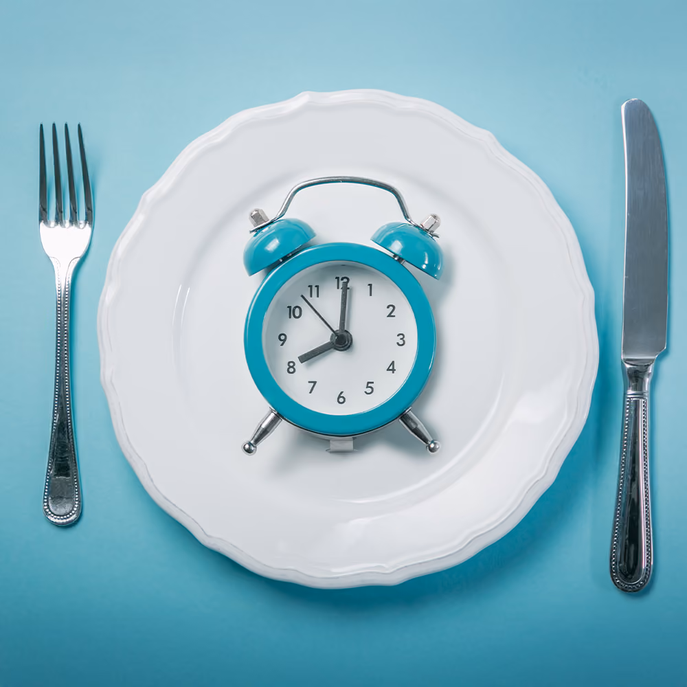 Clock on a dinner plate with cutlery, representing fasting.