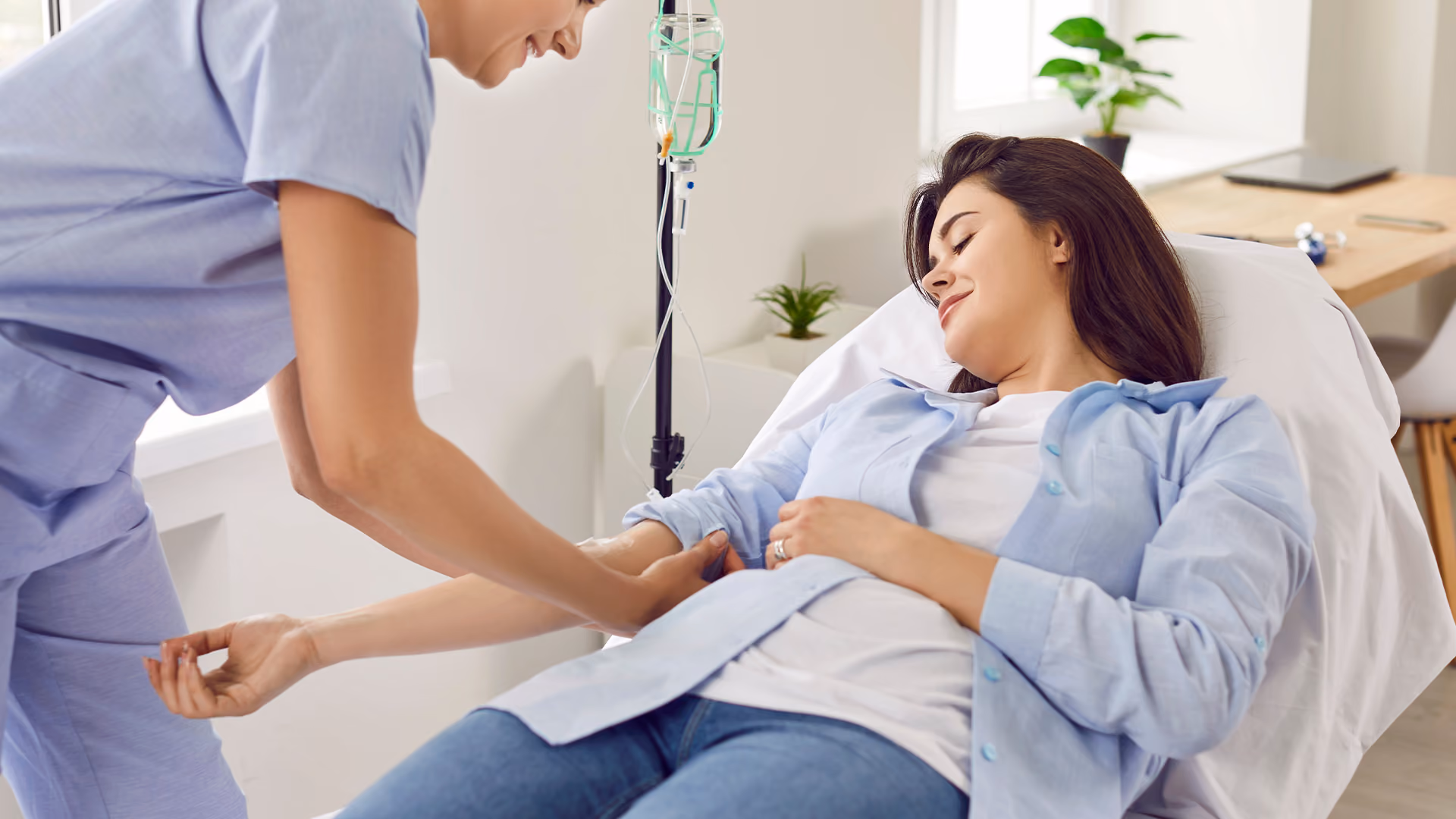 Nurse assisting a patient receiving an iron infusion through an IV while resting comfortably in a treatment chair.