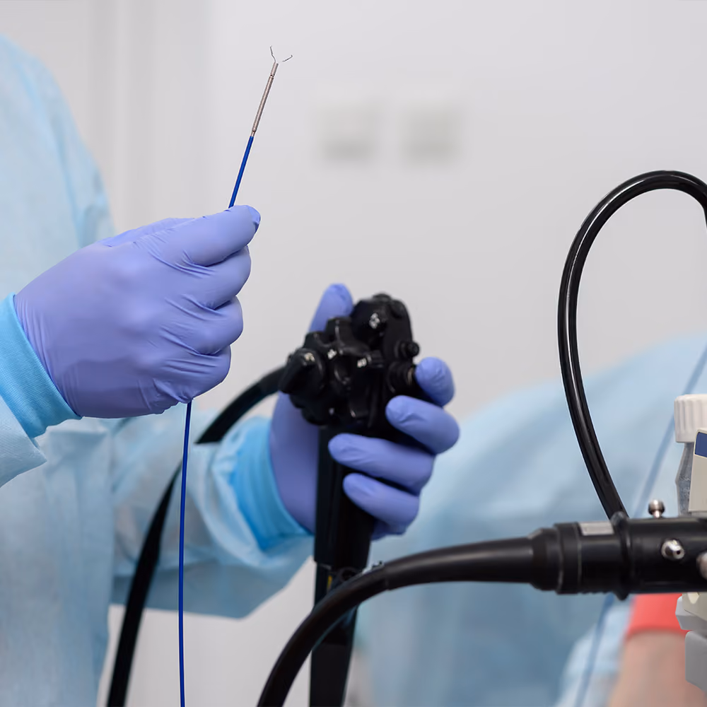 Clinician holding a gastroscope and endoscopic accessory before performing a gastroscopy procedure.