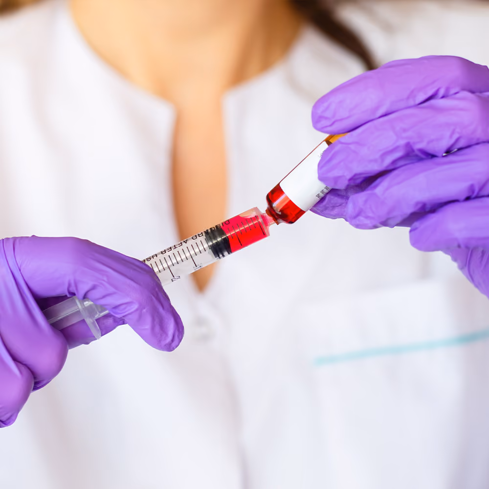 Healthcare professional preparing a vitamin B12 injection by drawing the solution into a syringe.
