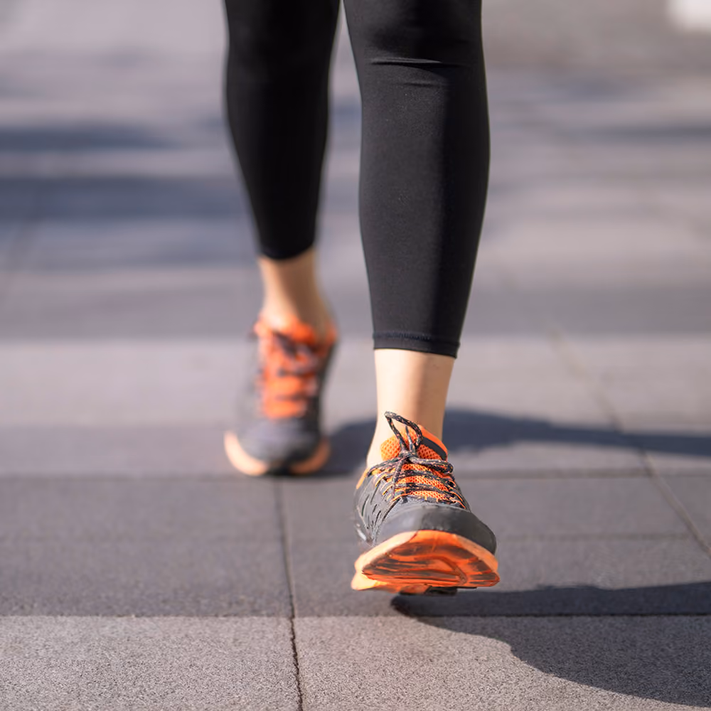 Person walking outdoors in athletic shoes, representing a return to normal daily activities after treatment.