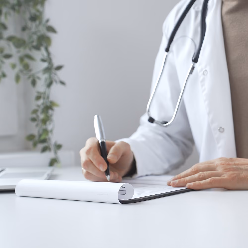 General practitioner completing a referral form during a consultation to arrange specialist assessment or further medical care.